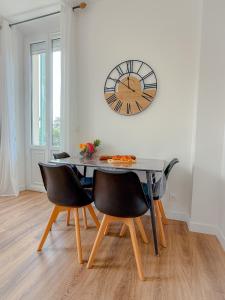 a dining room table with chairs and a clock on the wall at Le Margot By ApiRent #Climatisation #Wifi #Balcon in Cannes