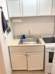 een keuken met witte kasten en een spoelbak bij Chelsea Studio-Shared Bathroom with Kitchen Twin Bunk Bed in New York