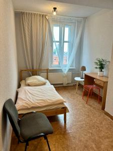 a bedroom with a bed and a desk and a window at Hostel J17 in Katowice