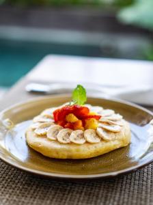 a pancake with fruit on a plate on a table at Kemari Ubud in Ubud