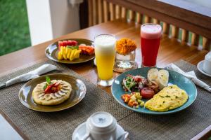 a table with two plates of food and two glasses of juice at Kemari Ubud in Ubud +66 photos