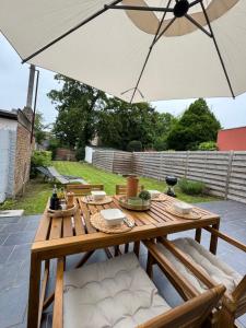 a wooden table with an umbrella on a patio at Maison proche de Pairi Daiza in Soignies
