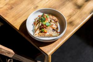 a bowl of food sitting on a wooden table at Blossom Eco Luxe Villas by Ekosistem in Canggu