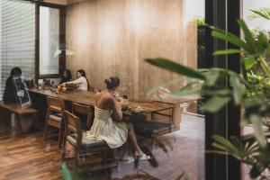 a woman sitting at a table in a restaurant at Blossom Eco Luxe Villas by Ekosistem in Canggu
