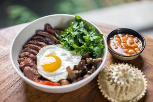 a bowl of breakfast food with an egg and mushrooms at Blossom Eco Luxe Villas by Ekosistem in Canggu