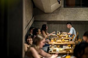 a group of people sitting at tables in a restaurant at Blossom Eco Luxe Villas by Ekosistem in Canggu