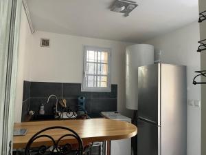 eine Küche mit Holztisch und Kühlschrank in der Unterkunft Logement indépendant Au Bonheur cuisine piscine clim proche centre village #dentelles Montmirrail in Beaumes-de-Venise