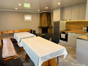 a kitchen with two tables and a stone fireplace at Sunny House in Madzhare