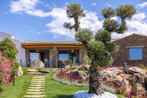 ein Haus mit einem Garten mit einem Baum im Hof in der Unterkunft Menhir Boutique Apartments- Adult Only- by Obiettivo vacanza Budoni in Tanaunella