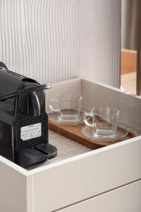 a coffee maker and two glasses on a counter at Olenia Suites in Neos Marmaras