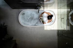 a man laying in a bath tub in a bathroom at Blossom Eco Luxe Villas by Ekosistem in Canggu