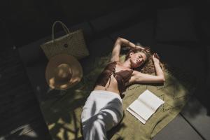 a woman laying on a bed with a book at Blossom Eco Luxe Villas by Ekosistem in Canggu