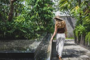 a woman wearing a hat walking through a fountain at Blossom Eco Luxe Villas by Ekosistem in Canggu