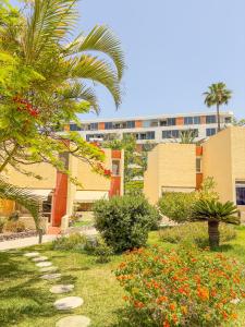 un giardino con alberi e fiori di fronte a un edificio di Cortijo a Playa de las Americas