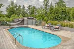 a pool with chairs and a hammock on a wooden deck at Parkvillan  +17 photos