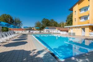 a swimming pool at a hotel with chairs and a building at Hotel & Residence Parador in Cesenatico