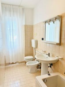 a white bathroom with a toilet and a sink at Maredena - Comodo al centro e al Mare - Immobil Relax in Lido di Jesolo