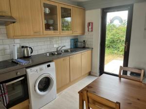 a kitchen with a washing machine and a wooden table at 39 Perran View Your Home Away from Home in Cornwall in St. Agnes
