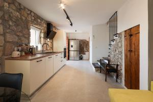 cocina con armarios blancos y pared de piedra en Villa Ana, en Prizna