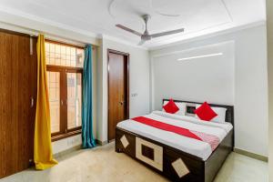 a bedroom with a bed with red pillows and a window at Hotel O South Plaza in New Delhi