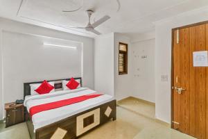 a bedroom with a bed with red pillows and a door at Hotel O South Plaza in New Delhi