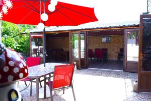 a table and chairs with a red umbrella on a patio at Casa Pestera Ponicova in Dubova