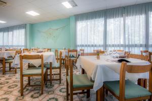 a dining room with tables and chairs and windows at Hotel & Residence Parador in Cesenatico