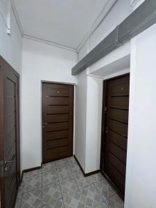 a hallway with two doors and a tiled floor at Room Hostel Tolebi in Almaty