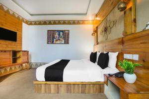 ムスーリーにあるTownhouse Oak Mussoorie Lakeのベッドとテレビがあるホテルの部屋