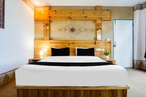 ムスーリーにあるTownhouse Oak Mussoorie Lakeの木製のヘッドボードが付いた大きな白いベッドのある寝室
