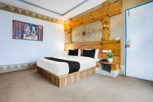 ムスーリーにあるTownhouse Oak Mussoorie Lakeの木製のヘッドボードが付いた大きなベッドのある寝室