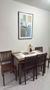 a dining room table with two chairs and a painting at JV tRansient 24 in Ormoc