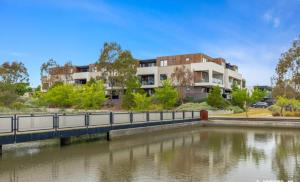 a bridge over a river in front of a building at Lakeside Retreat in Caroline Springs