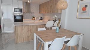 a kitchen with a wooden table and white chairs at Casa Virginia in Los Alcázares
