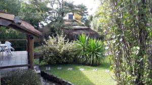 a garden with a thatched hut in the background at Cabañas Pedras Moras in Tanti