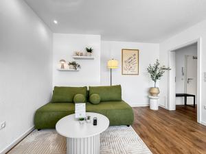 a living room with a green couch and a table at Modernes Apartment 'Ulla' in Diepholz in Diepholz