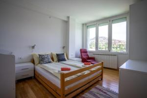a bedroom with a bed and a red chair at Capital Stay in Sarajevo