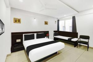 a bedroom with a bed and a couch and a tv at Townhouse Oak City Center Mysore Palace in Mysore