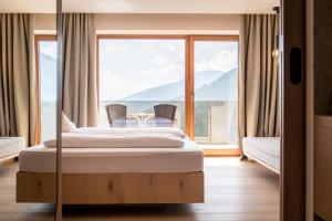 sypialnia z łóżkiem i dużym oknem w obiekcie Kronplatz-Resort Hotel Kristall w mieście Valdaora