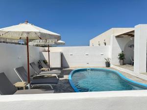 a swimming pool with chairs and an umbrella at Villa Echedra in Vlychada