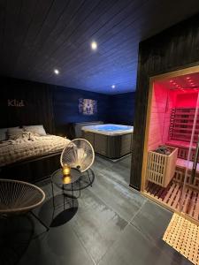 a room with a bed and a tub and tables at Wooden SPA in Hradec Králové +2 photos