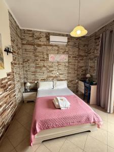 a bedroom with a pink bed with a brick wall at 2-Bed Blue & White Apartment with Jacuzzi, BBQ, Garden, near Beach in Platanias