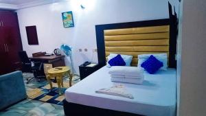 Schlafzimmer mit einem Bett mit blauen Kissen und einem Schreibtisch in der Unterkunft GRAND PARK HOTEL AND SUITEs in Egbe