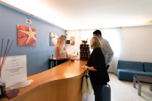 a group of people standing at a counter in a salon at Hotel & Residence Parador in Cesenatico +46 photos