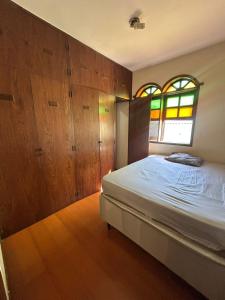 a bedroom with a bed and some wooden cabinets at Casa 5 quartos entre Centro e Pampulha in Belo Horizonte