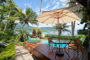 a patio with a table and chairs and an umbrella at Casa da Ilha & SPA in Abraão