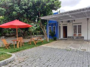 a patio with a table and a red umbrella at Rumah Inap Pesanggrahan in Giri