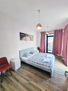 a bedroom with two beds and a red chair at Apartmany Paradiso Shekvetili in Shekvetili