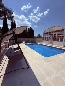 a chair and an umbrella next to a swimming pool at Luxury Villa con piscina y tenis privados in Argés