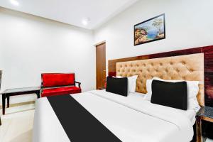 a bedroom with a large bed and a red chair at Townhouse Oak Paharganj Delhi Railway Station in New Delhi